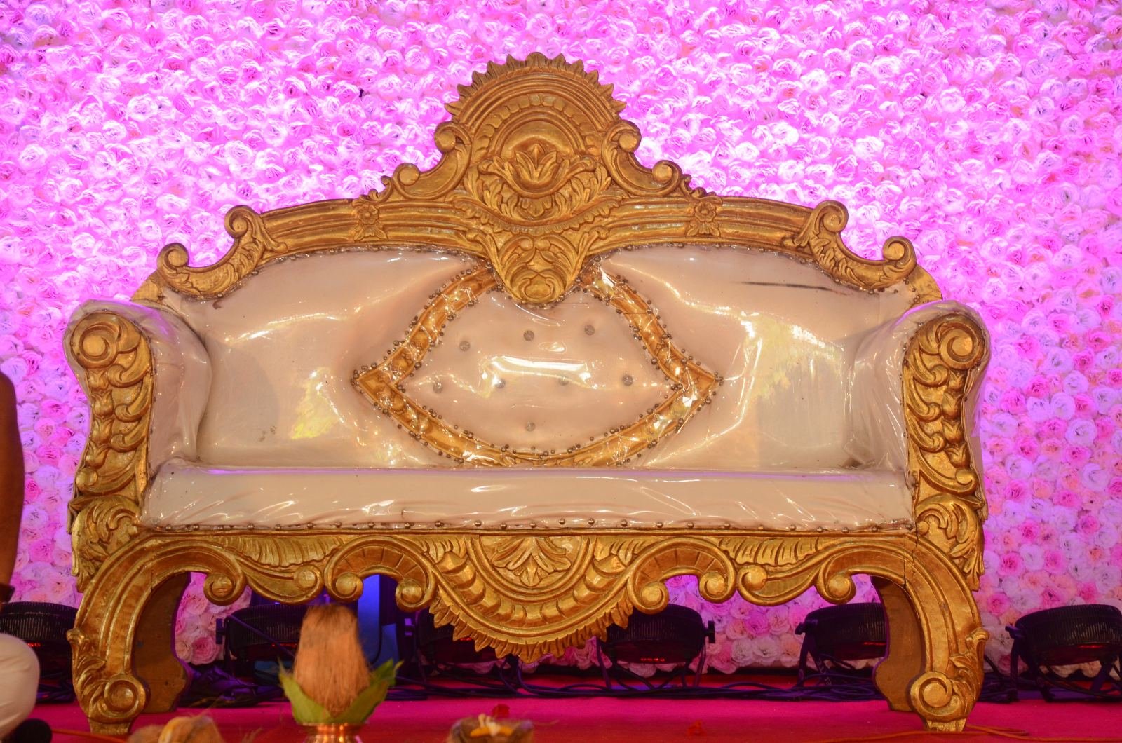 Royal golden sofa for bride and groom on a pink floral stage